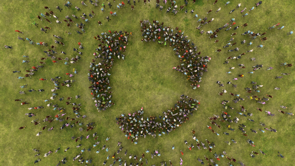 An aerial shot of a large group of people coming together to make the recycling symbol.